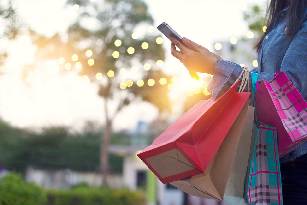 Woman usingsmartphone with shopping bag in hands